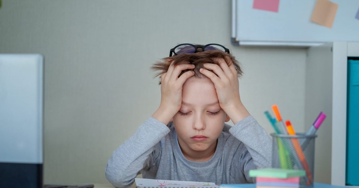 Frustrated child with hands in hair struggling to focus on homework, showing signs of ADHD